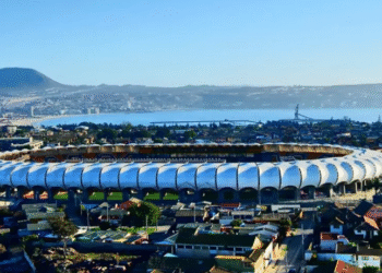 Estádio em Valparaíso, Chile, destaca-se com sua arquitetura moderna, cercado por montanhas e com o mar ao fundo.