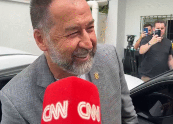 Augusto Melo revela detalhes das negociações com Dorival 32 Homem sorridente em entrevista, próximo a carro. Equipe de filmagem e fotógrafos ao fundo registrando o momento.