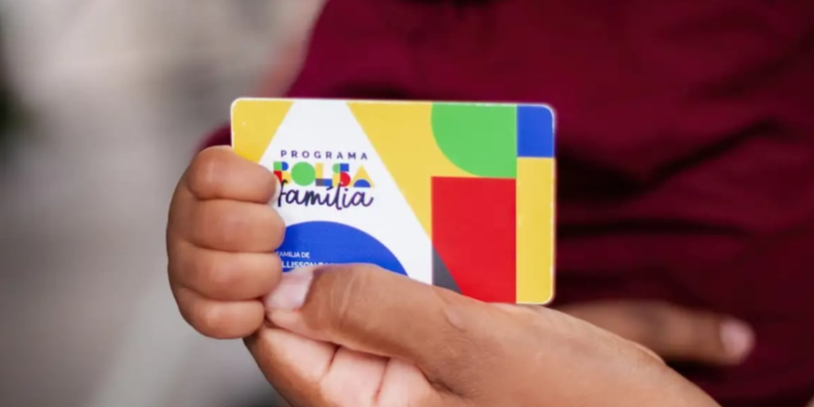 Criança segura cartão colorido do Programa Bolsa Família com ajuda de um adulto, destacando assistência social e inclusão.