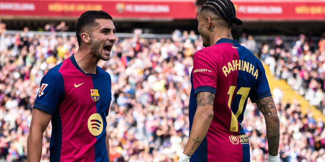Jogadores do Barcelona celebram um gol em campo, rodeados por torcedores no estádio vibrante e lotado.