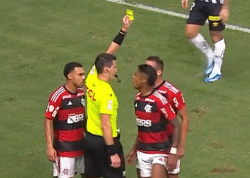 Bruno Henrique: Apostas alertam para manipulação suspeita 34 Árbitro mostrando cartão amarelo a jogador de futebol, cercado por companheiros de equipe. Partida tensa no campo.