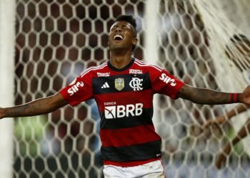 Bruno Henrique: Cartão de aposta revela fraude chocante! 33 Jogador de futebol do Flamengo comemora gol com expressão de alegria em frente ao gol, braços abertos, em campo de futebol.