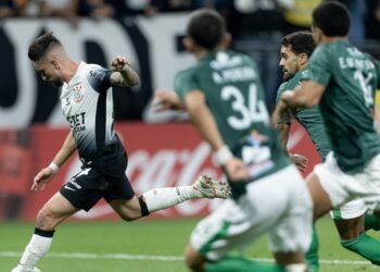 Jogador do Corinthians chuta bola sob pressão de atletas do América-MG durante partida de futebol competitivo.