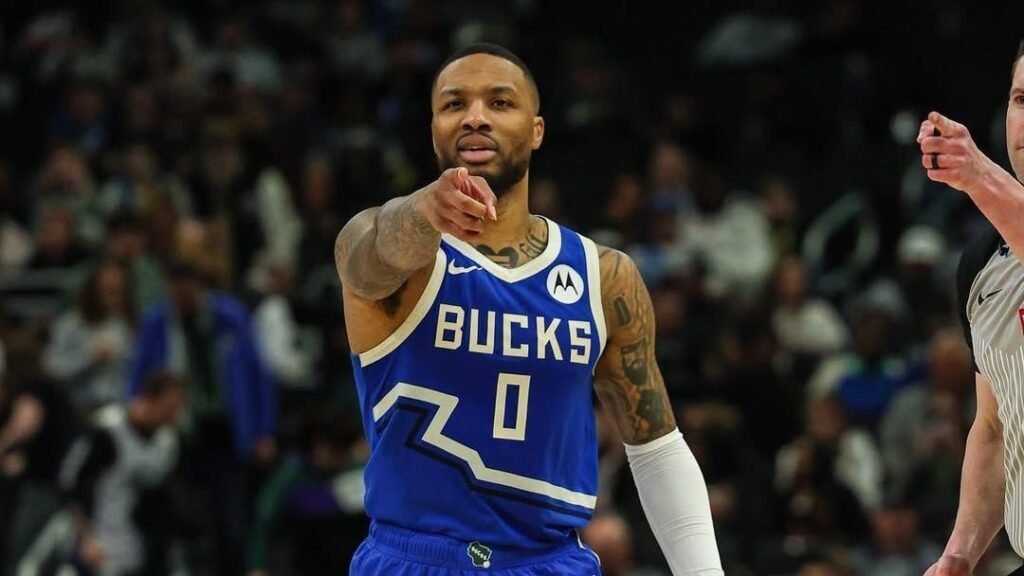 Jogador de basquete do Milwaukee Bucks em quadra, usando uniforme azul, aponta, concentrado durante o jogo.