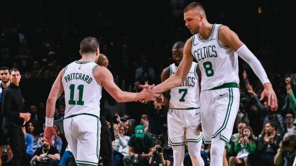Jogadores dos Celtics celebram em quadra durante jogo, demonstrando união e trabalho em equipe no basquete profissional.