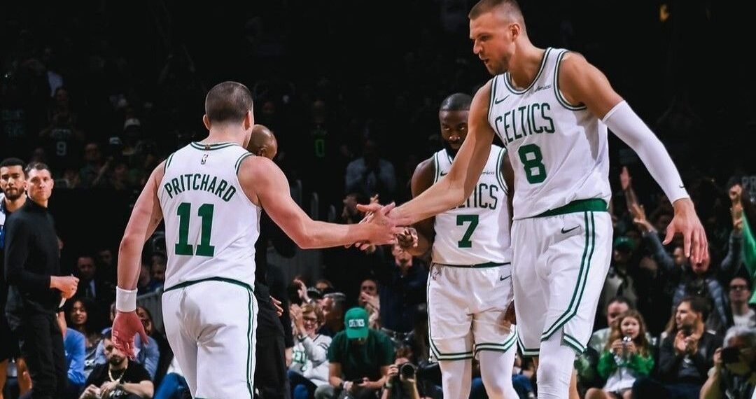 Jogadores dos Celtics celebram em quadra durante jogo, demonstrando união e trabalho em equipe no basquete profissional.