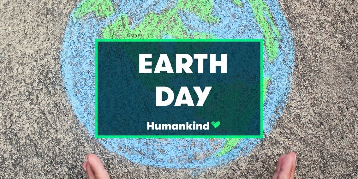 Desenho de giz no chão com um planeta Terra e mãos ao redor, destacando a mensagem Earth Day e Humankind.