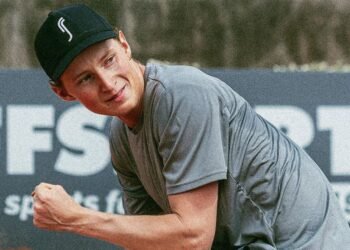 Elmer Moller: Oponente de João Fonseca no Madrid Open 2023 33 Jovem com boné preto e camiseta cinza comemora ao ar livre, exibindo expressão sorridente diante de um fundo esportivo.