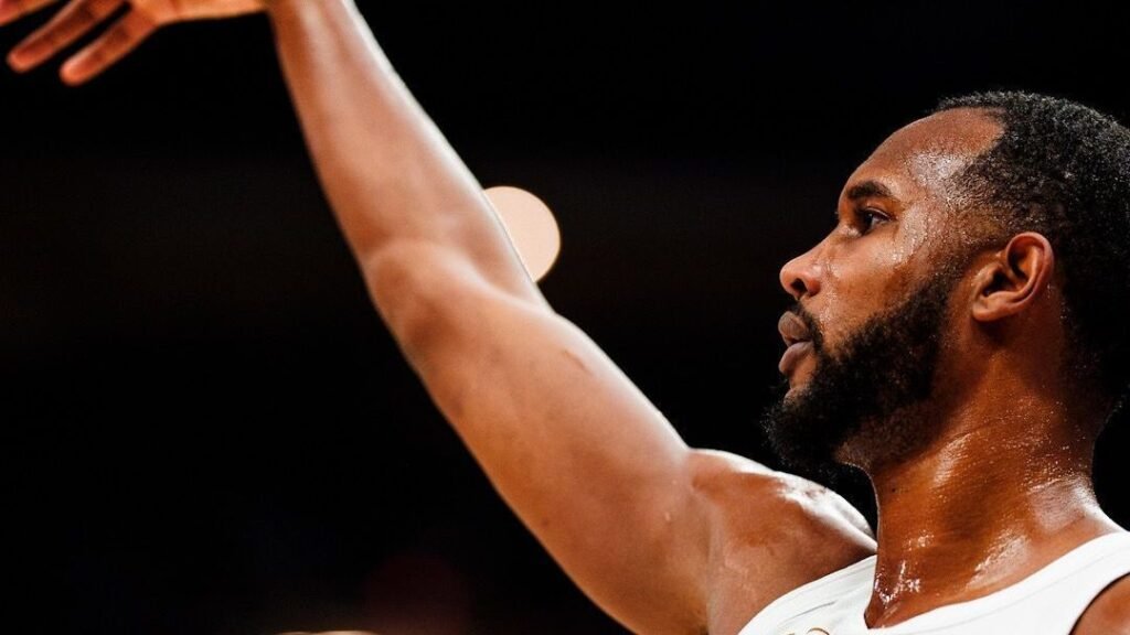 Jogador de basquete arremessando bola em quadra, destacando foco e intensidade do movimento esportivo.