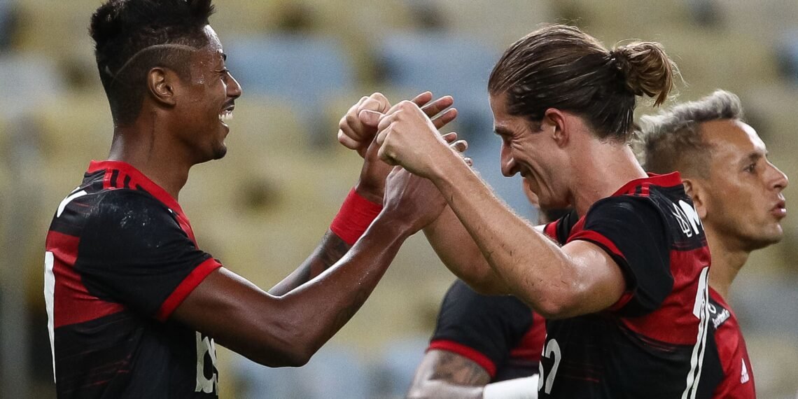 Jogadores do Flamengo comemoram gol com abraços e sorrisos no estádio, destacando união e emoção no futebol brasileiro.