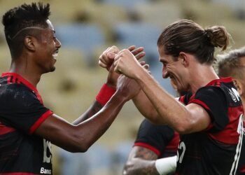 Jogadores do Flamengo comemoram gol com abraços e sorrisos no estádio, destacando união e emoção no futebol brasileiro.