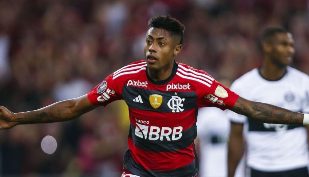 Jogador do Flamengo comemora após marcar um gol, vestindo uniforme rubro-negro, em partida de futebol competitivo.
