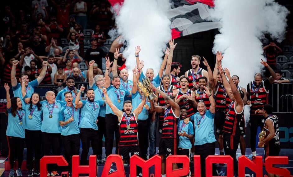 Equipe de basquete vence campeonato, comemorando com troféu em mãos, uniformes vermelhos e pretos, e fumaça branca.
