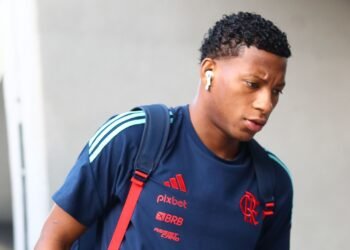 Flamengo divulga lesão de Gonzalo Plata e próximo planejamento 36 Pessoa com camiseta esportiva azul e vermelho, usando fones de ouvido, segura uma mochila e olha para baixo, caminhando.