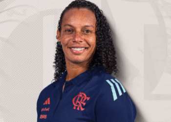 Flamengo feminino faz história com primeira treinadora mulher 37 Pessoa sorridente vestindo uniforme do Flamengo, destacando símbolos do time no cenário neutro.