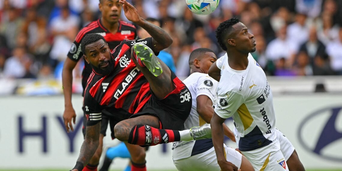 Jogador do Flamengo realiza bicicleta em campo disputando bola com adversários durante partida de futebol movimentada.