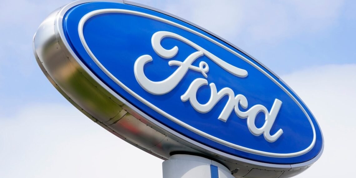 Logotipo da Ford em grande placa azul oval, destacando-se contra o céu, simbolizando inovação automotiva.