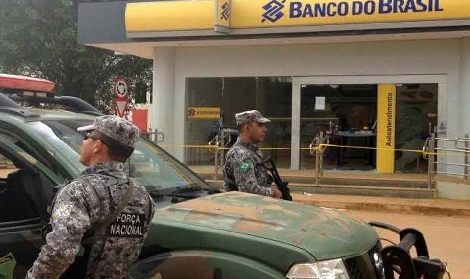 Segurança da Força Nacional em frente ao Banco do Brasil, com viatura militar, reforçando vigilância no local.