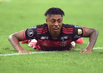 Indiciados no Caso Bruno Henrique: família na investigação 38 Jogador de futebol do Flamengo deitado no gramado durante partida, expressando determinação e esforço no jogo.