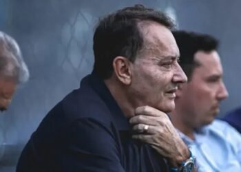 Investimentos do Cruzeiro em contratações: 2024 em números 35 Homens sentados lado a lado, em perfil, com expressões concentradas, em ambiente externo, possivelmente observando algo.