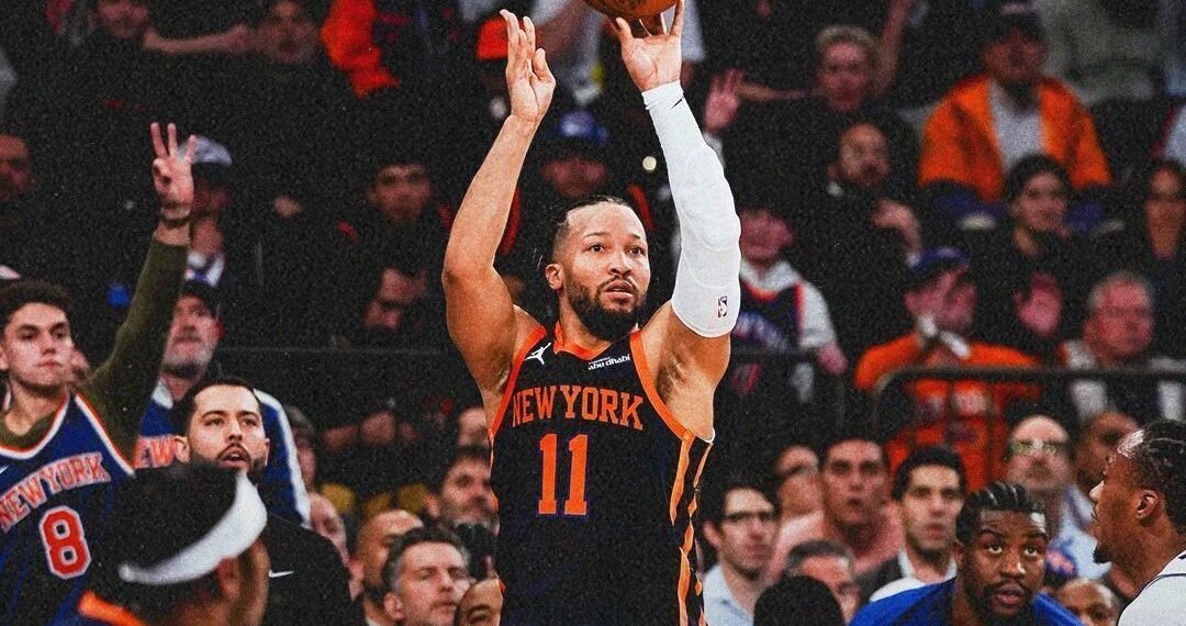 Jogador do New York Knicks arremessa bola de basquete em quadra lotada, enquanto torcida observa atenta a jogada decisiva.