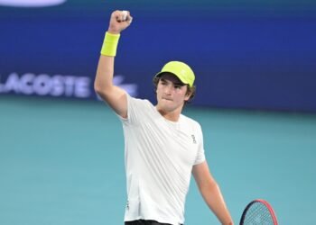 João Fonseca: Estreia emocionante em Roland Garros 2024 36 Tenista celebra com punho erguido, usando boné e munhequeira amarela, em quadra de piso azul.