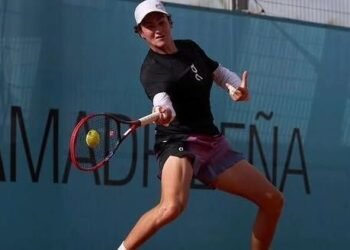 João Fonseca vence Elmer Moller no Madrid Open: confira! 36 Jogador de tênis se prepara para rebater uma bola em quadra, usando boné e roupa esportiva, com uma parede azul ao fundo.