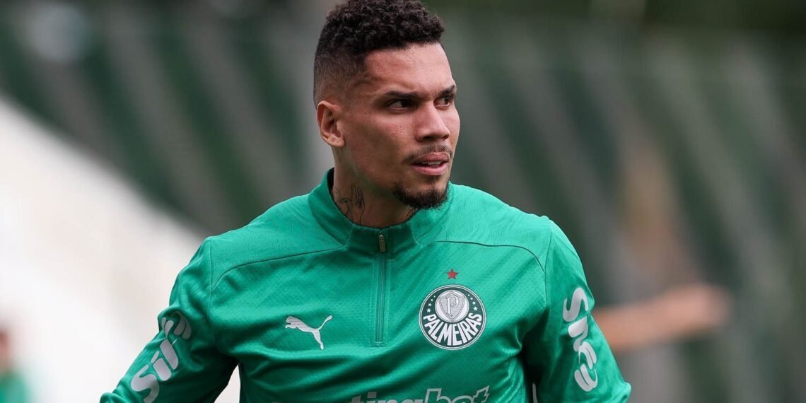 Jogador do Palmeiras em uniforme verde, observando atento ao campo, com expressão focada durante treinamento de futebol.