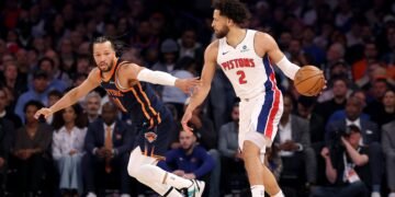Jogadores de basquete de Knicks e Pistons disputam a posse da bola em uma partida cheia de energia e competição.