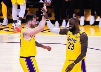 Quem Domina a NBA? A Verdade por Trás da Competição! 33 Jogadores de basquete dos Lakers celebrando com um high-five durante partida, vestindo uniformes amarelos e sorrindo.