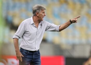 Renato Gaúcho critica VAR: 'CBF entrega Ferrari a cego' 31 Técnico de futebol gesticula intensamente à beira do campo, vestindo camisa social e jeans, em estádio com arquibancadas desfocadas.