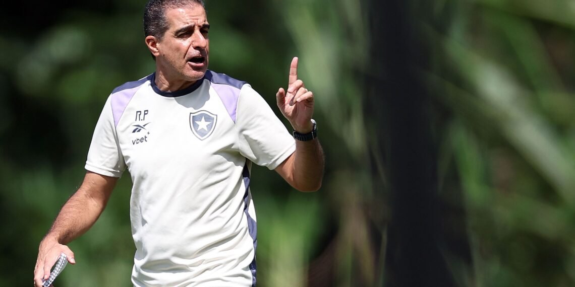Homem com uniforme esportivo do Botafogo gesticula durante treino ao ar livre, em meio a um cenário de vegetação verde.
