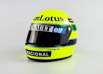 Capacete de corrida amarelo com logotipos de patrocinadores como Lotus, Renault, elf e Nacional, design icônico e visor escuro.