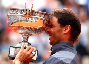 Roland Garros fará tributo a Rafael Nadal, lenda do tênis 33 Tenista celebra vitória pressionando o rosto contra um grande troféu prateado em um torneio de tênis.