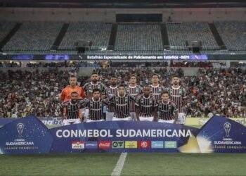 Jogadores do Fluminense posam no Maracanã para foto antes de partida da Copa Sul-americana, com grande torcida ao fundo.