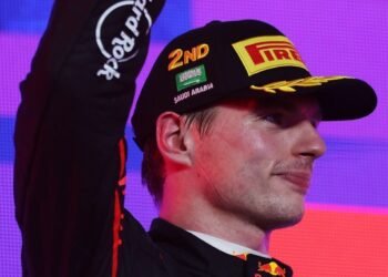 Piloto de Fórmula 1 com boné de segundo lugar, saudando o público após corrida na Arábia Saudita, expressão confiante.