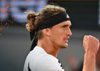 Zverev reage a insulto: torcedor expulso por ofensa 40 Jogador de tênis celebra vitória com punho erguido, usando camisa branca e faixa preta, em ação focada e determinada.