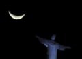 20.jul.2015 - Cristo Redentor, no Rio de Janeiro, com a Lua crescente ao fundo, em vista do bairro de Botafogo
